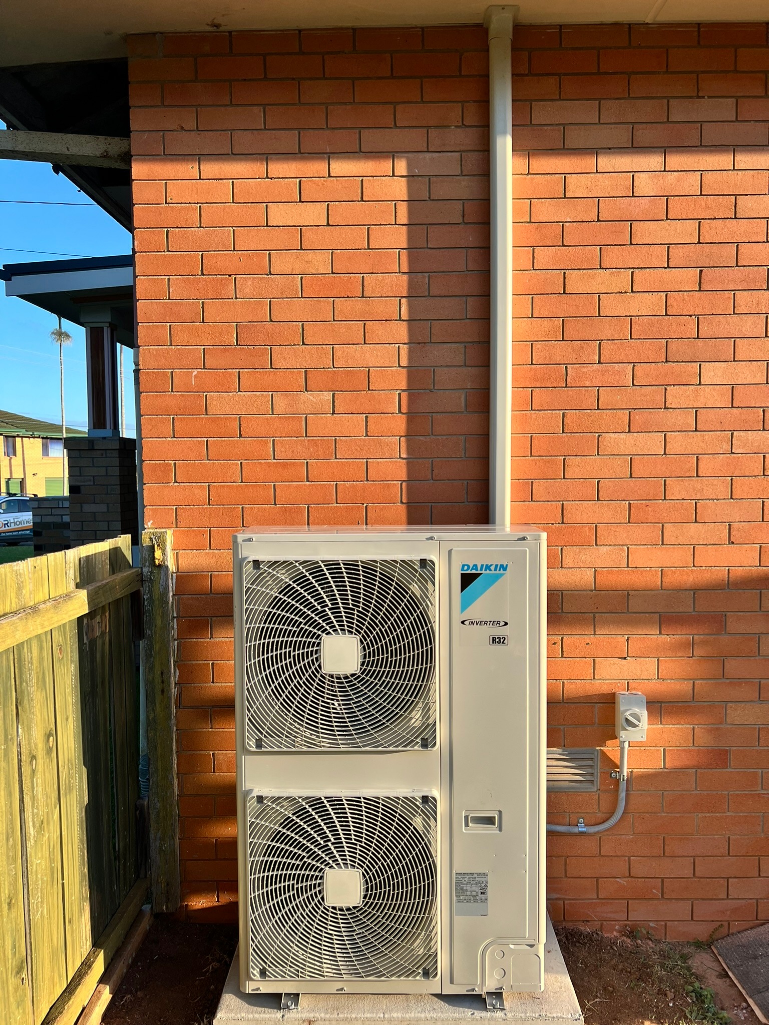 Large Daikin ducted outdoor unit installed neatly against a brick wall.