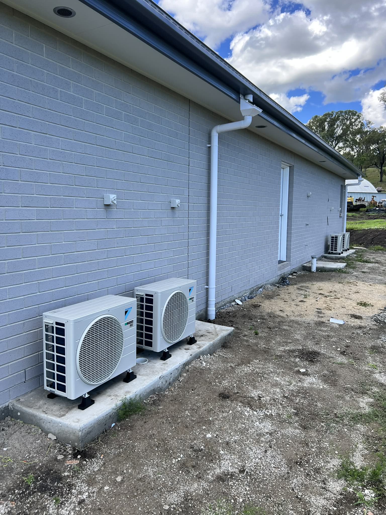 Multiple Daikin outdoor units installed neatly along the side of a new home.