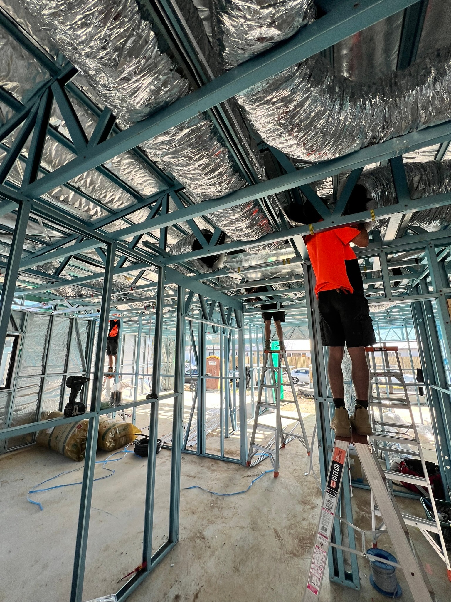 Coretemp team carrying out ducted air conditioning rough-in work inside a steel-frame home.
